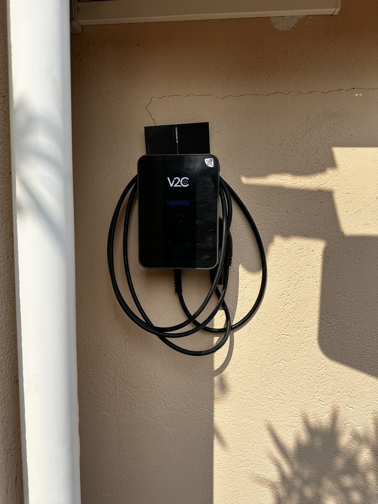 Cargador V2C en pilar turquesa de parking moderno